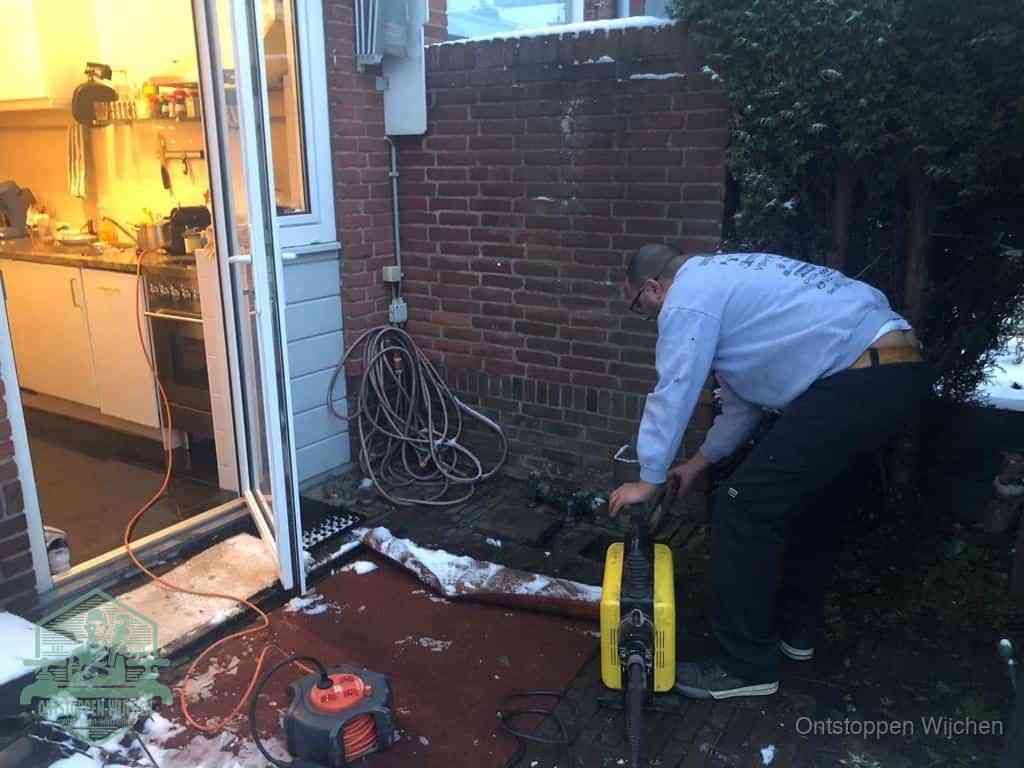 Een monteur werkt buiten bij een open riool-/grondput met een elektrische ontstoppingsmachine om een verborgen afvoerprobleem op te sporen in Wijchen