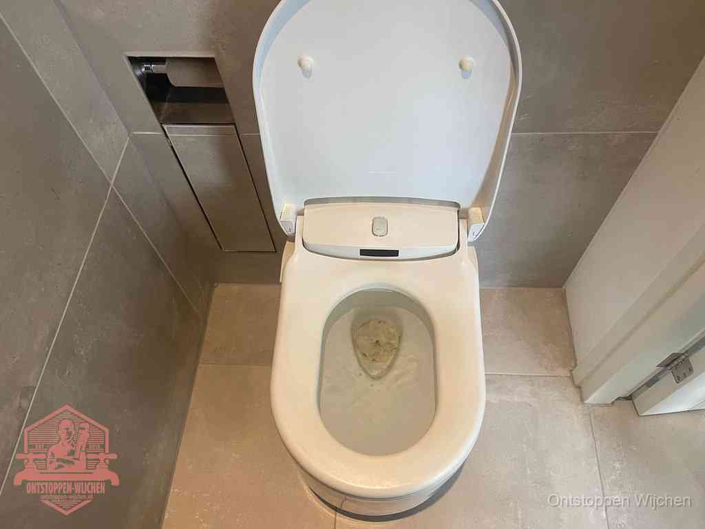 Een wit hangtoilet waarin een prop wc-papier op het water blijft drijven, een duidelijk signaal van een verstopte wc in Wijchen