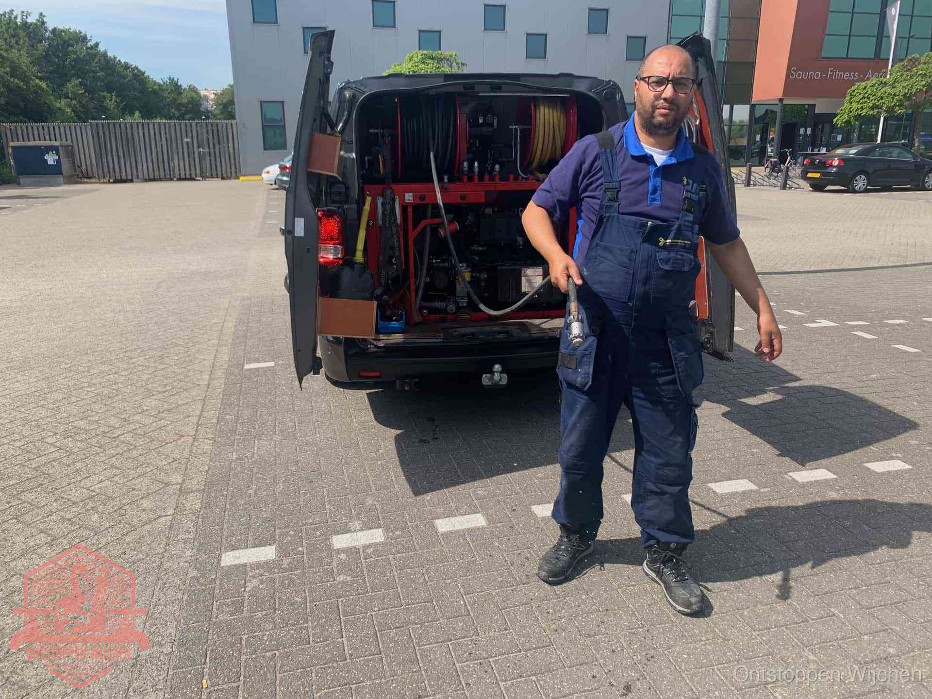 Een monteur bij zijn bestelbus met een hogedruk- en rioolreinigingsunit, klaar om de oorzaak van terugkerende wc-verstoppingen aan te pakken in Wijchen